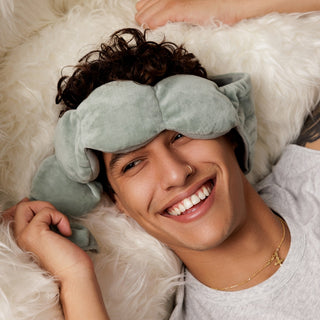 Noppod Weighted Sleep Eye Mask - Sage
Person wearing a light blue eye mask on a fluffy white surface