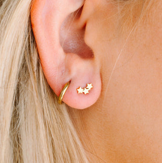 Pierced Co. Triple Star Earrings
Close-up of an ear wearing gold earrings with star designs.