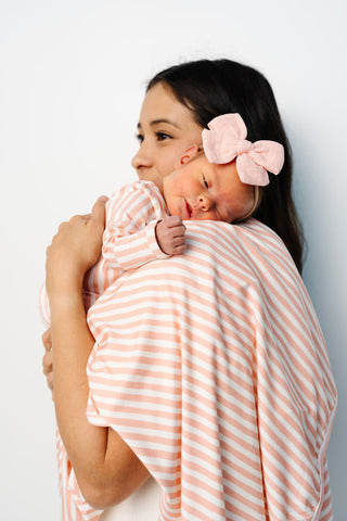 Lou Lou and Company Swaddle Blanket - Brynn
Woman holding a baby wrapped in a pink and white striped blanket against a light gray background