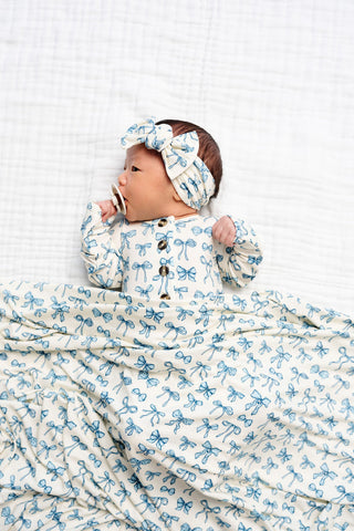 Lou Lou and Company Top and Bottoms - Stella
Baby swaddled in a blue and white patterned blanket with a matching headband.