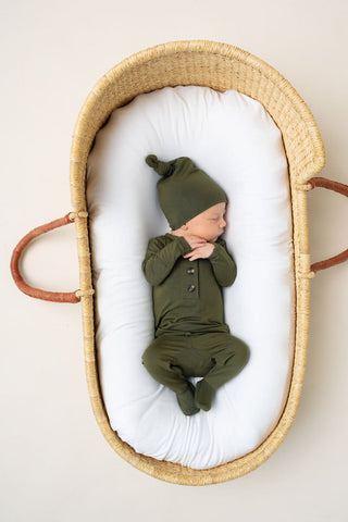 Lou Lou and Company Top and Bottoms - Riley
Newborn baby in a green outfit and hat lying in a wicker Moses basket with white sheet.