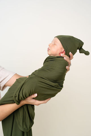 Lou Lou and Company Swaddle Blanket - Riley
Newborn baby wrapped in a green swaddle with a matching hat, held by a person against a plain background.