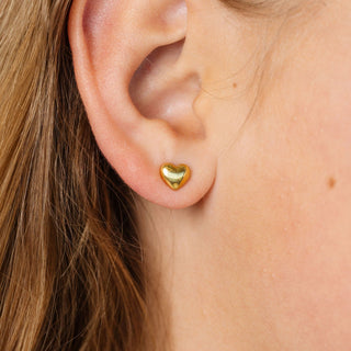 Pip Pop Post Earrings - Bubble Heart stud
A close-up of a person's ear wearing a small polished gold heart stud earring.