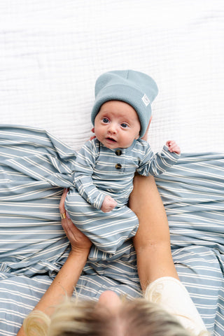 Lou Lou and Company Knotted Gown - Wells
Baby in blue striped outfit and hat lying on a striped blanket