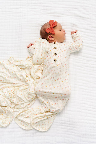 Lou Lou and Company Knotted Gown - Willow
Newborn baby wrapped in a white swaddle with gold buttons on a white background