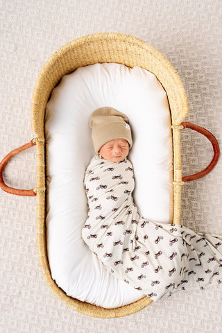 Lou Lou and Company Swaddle Blanket - Cruz
Newborn baby swaddled in a patterned blanket, lying in a woven basket on a neutral background