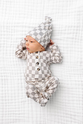 Lou Lou and Company Top and Bottoms - Palmer
Baby in checkered outfit and hat lying on a white textured surface