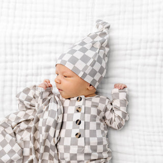 Lou Lou and Company Knit Top Knot Hat - Palmer
Baby wearing a gray and white checkered outfit and hat on a white background