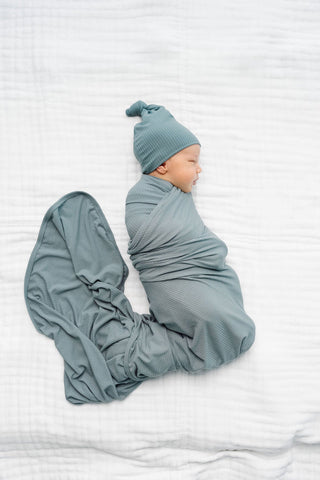 Lou Lou and Company Ribbed Swaddle Blanket - Ford
Newborn baby swaddled in a matching blue outfit on a white background