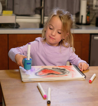 The Pencil Grip Inc Air Colors Airbrush Kit 
Young girl drawing with markers on a notebook at a kitchen table.