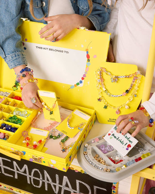 Super Smalls Super Entrepreneur Bead Kit Children playing with a jewelry-making kit from Lemonade, featuring colorful beads and tools.