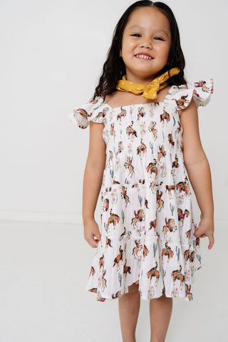 Alto Modas Girls Daphne Dress - Western
Young girl wearing a white dress with horse print and a yellow scarf on a white background