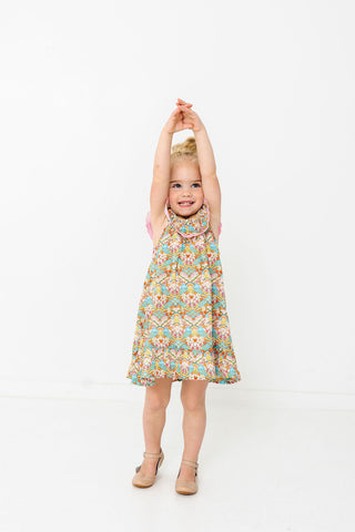 Alto Modas Girls Harper Dress - Happy Sun
Young girl in a floral dress standing with arms raised on a white background