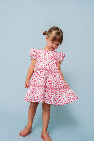 Alto Modas Girls Twirl Dress - Hearts Print
Young girl wearing a red and white patterned dress against a light blue background
