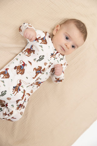Angel Dear 2 Way Zipper Footie - Buckaroo Western
Baby wearing a onesie with cowboy print lying on a beige surface