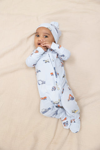 Angel Dear 2 Way Zipper Footie - Construction Vehicles
Baby in a white onesie with vehicle prints and a matching hat, lying on a beige blanket.