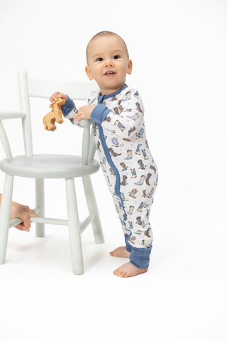 Angel Dear 2 Way Zipper Romper - Cowboy Boots
Baby in a cowboy-themed onesie standing next to a white chair on a white background