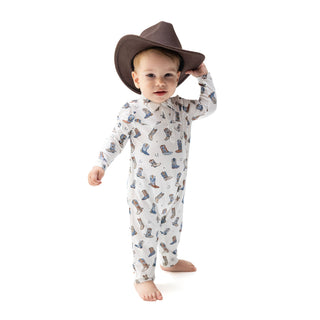Angel Dear Long Sleeve Cowboy Romper - Buckaroo Boots
A baby wearing a brown cowboy hat and a white long-sleeve footless onesie with a blue and brown cowboy boot print, standing against a white background.
