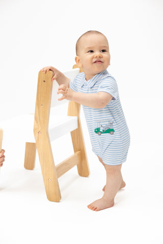 Angel Dear Polo Shortie - Striped Golf
Baby in a striped outfit standing next to a wooden stool on a white background