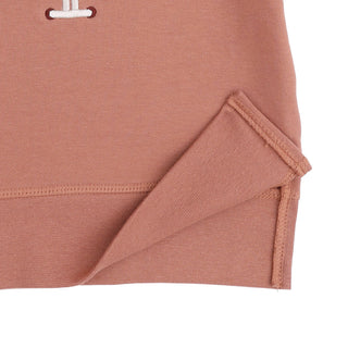 Angel Dear Raglan Sweatshirt and Jogger Set - Football Laces
Close-up of a dusty rose pink knit garment, showing the folded hem and a small white embroidered detail on a plain white background.
