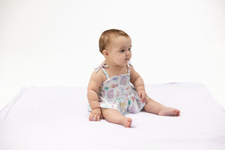 Angel Dear Smocked Bubble with Skirt - Beach Days
Baby sitting on a white surface wearing a patterned outfit.