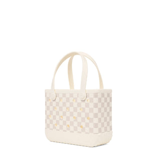 Bitty Bogg® Bag - Checkered: Coconut / Mushroom
A small structured tote bag in a light beige and off-white checkerboard pattern with small gold star accents and cream-colored shoulder straps, shown on a plain white background.