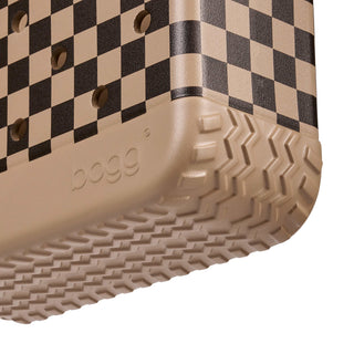 Bitty Bogg® Bag - Checkered: Camel / Hot Cocoa
Close-up of a beige and black checkerboard clog shoe showing the textured beige outsole and the embossed 'bog' brand logo.