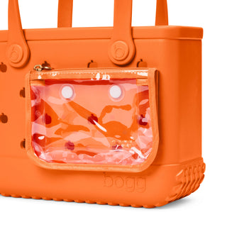 Bitty Bogg® Bag - Pieces of Pumpkin
An orange Bogg tote bag with a clear front pouch containing a pink camouflage pattern, shown on a white background.