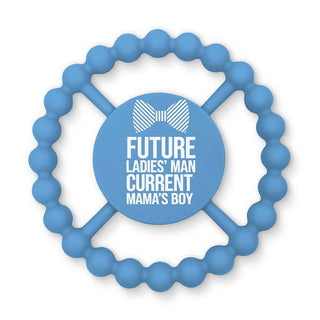 Bella Tunno Happy Teether - Future Ladies Man
A light blue silicone baby teether with a circular beaded outer ring and a central round pad. The center features white text that reads 'FUTURE LADIES' MAN CURRENT MAMA'S BOY' with a white bowtie graphic above, on a clean white background.