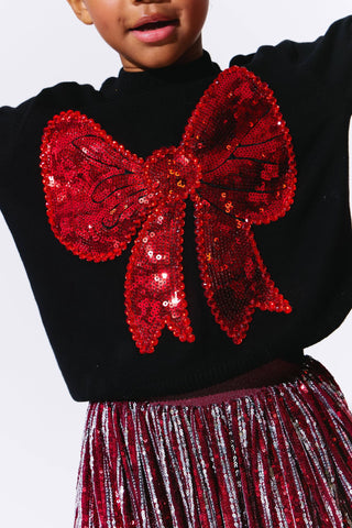 Lola and The Boys Big Bow Sweater
Black sweater with a large red sequin bow and red sequin skirt on a white background