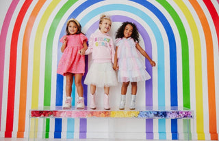 Lola and The Boys Birthday Girl Hoodie
Three children standing in front of a colorful rainbow-striped backdrop