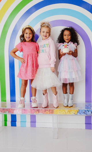 Lola and The Boys Birthday Girl Hoodie
Three children in colorful outfits standing in front of a rainbow arch