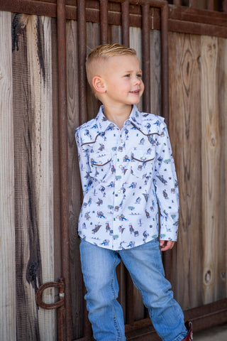 BlueQuail Clothing Co Pearl Snap Long Sleeve Shirt - Rodeo
A young boy wearing a white long-sleeve western shirt with a blue and brown animal print, paired with blue jeans, standing in front of a rustic wooden gate.