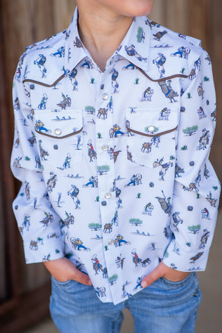 BlueQuail Clothing Co Pearl Snap Long Sleeve Shirt - Rodeo
A child wearing a white western-style button-up shirt with a blue and brown cowboy and horse print, paired with blue jeans.