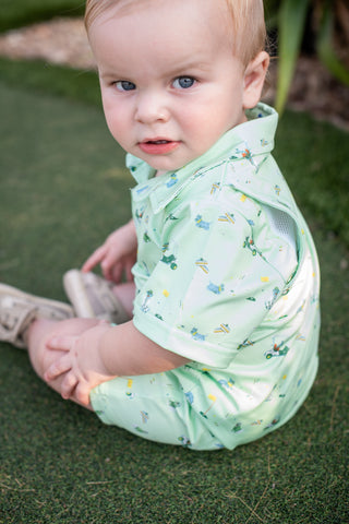 BlueQuail Clothing Co Polo Short Sleeve Romper - Dogwood
Baby wearing a light green outfit with a pattern, sitting on grass.
