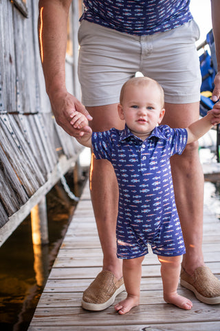 BlueQuail Clothing Co Polo Short Sleeve Romper - Freshwater
Baby in a blue outfit standing on a wooden dock with an adult holding their hands.