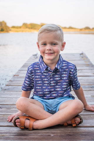 BlueQuail Clothing Co Polo Short Sleeve Shirt - Freshwater
Young boy sitting on a wooden dock by a body of water, wearing a patterned shirt and shorts.