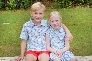 BlueQuail Clothing Co Polo Sleeveless Dress - Stars & Stripes
BlueQuail Clothing Co Polo Short Sleeve Shirt - Stars & Stripes
Two children in matching outfits sitting on a stone ledge outdoors.