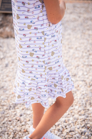 BlueQuail Clothing Co Polo Sleeveless Dress - 7th Inning Stretch
Person wearing a white dress with colorful patterns on a pebbly surface