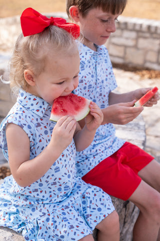 BlueQuail Clothing Co Polo Sleeveless Dress - Stars & StripesTwo children in matching outfits eating watermelon outdoors.