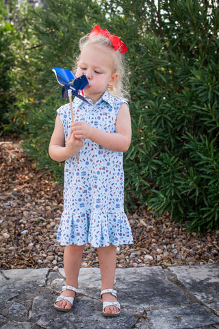 BlueQuail Clothing Co Polo Sleeveless Dress - Stars & Stripes
Young girl in a floral dress holding a blue and red pinwheel outdoors.