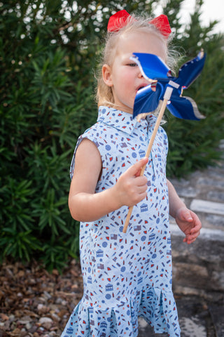 BlueQuail Clothing Co Polo Sleeveless Dress - Stars & Stripes
Young girl in a patterned dress holding a blue pinwheel against a natural background