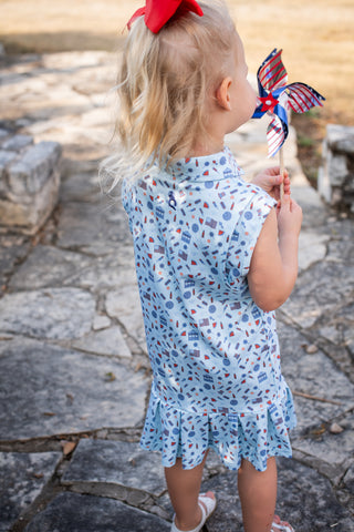 BlueQuail Clothing Co Polo Sleeveless Dress - Stars & Stripes
Child in a blue dress with a red, white, and blue pinwheel on a stone path.