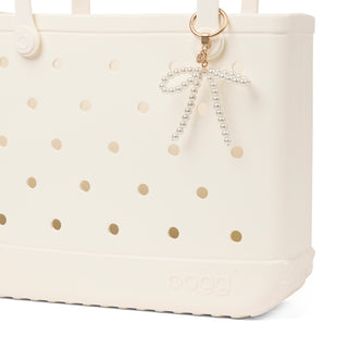 Bogg'd & Charmed - White Pearl Bow
White tote bag with gold polka dots and a decorative keychain on a white background