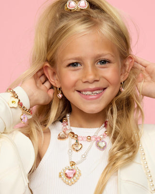 Sweetheart Surprise Lipgloss Locket
Young girl wearing pink and gold jewelry against a pink background
