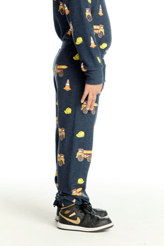 Chaser Construction Trucks Pants'Dark blue sweatpants with construction vehicle pattern worn by a person on a white background