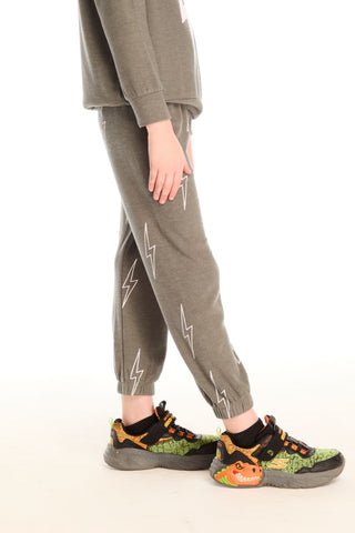 Chaser Allover Bolts Pants
Person wearing gray jogger pants with white lightning bolt patterns and colorful sneakers on a white background