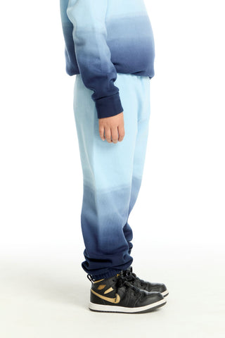 Chaser Malibu Blue Ombre Jogger
Person wearing a blue and gray gradient outfit with black sneakers on a white background