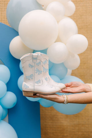 Baby blue cowgirl boots by Wild & Rae with a decorative bow, stylish western footwear for kids.