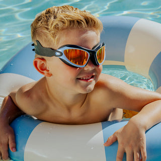 Bling2o Covert Chomp Shark Swim Goggles
Child wearing sunglasses with a fish design, sitting on an inflatable ring in a pool.